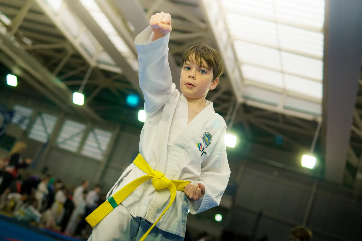 Small child in a white dobok holding a punch with a yellow belt